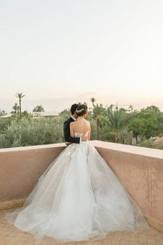 a bride and groom standing on a balcony looking out at the desert in palm trees