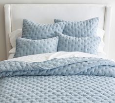 a bed with blue comforters and pillows on it