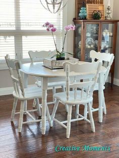 a dining room table with chairs and a vase on it's centerpiece in front of a window