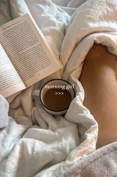 a person laying in bed with a book and cup of coffee