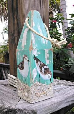 a birdhouse with three birds painted on it's side sitting on a wooden table