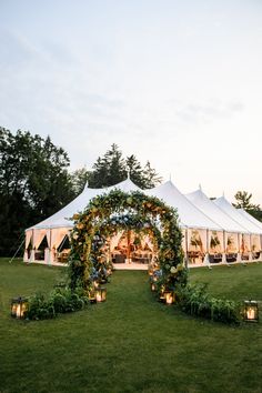 an outdoor tent with candles and greenery on the lawn