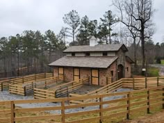 a horse barn with wooden fences surrounding it