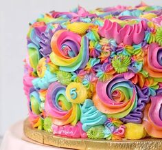 a multicolored cake with swirls and flowers on the top is sitting on a gold platter