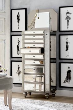 a silver jewelry cabinet sitting in front of pictures on the wall