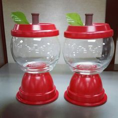 two clear glass bowls with green leaves on top and one red bowl has a lid