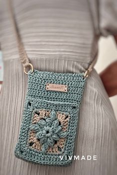 a woman is holding a crocheted purse in her hands and wearing a gray shirt