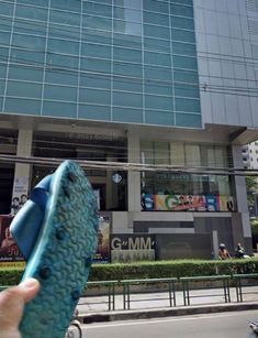 a person holding up a blue object in front of a building