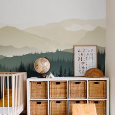 a baby's room with mountains painted on the wall and wicker baskets below