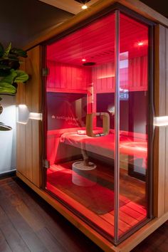 an indoor sauna is lit up with red light in the room and on the floor