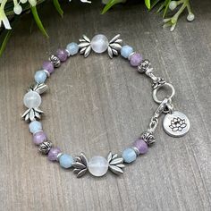 This stunning handmade crystal gemstone bead bracelet features  faceted genuine Aquamarine and Lavender Amethyst stones, 8 mm round Selenite beads, silver plated Lotus accent beads, and a Lotus Flower charm.  It is strung with stainless steel jewelry wire and features a lovely lobster claw clasp. This bracelet measures approximately 7.25 inches.  Sorry - sizing is NOT available on these toggle-style bracelets, but custom orders are welcome! Simply message me to find out more.   Aquamarine: promo Spiritual Lavender Jewelry With Faceted Beads, Lavender Spiritual Jewelry With Faceted Beads, Lavender Beaded Crystal Bracelet For Healing, Spiritual Moonstone Bracelets With Faceted Beads, Spiritual Lavender Gemstone Beaded Bracelets, Spiritual Lavender Gemstone Beaded Bracelet, Gemstone Beaded Bracelets, Amethyst Stone, Stainless Steel Jewelry