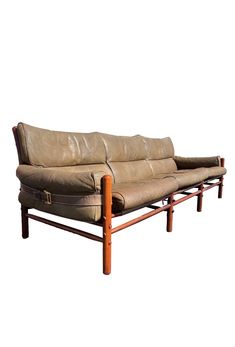 a tan leather couch with wooden legs and arm rests against a white background, it appears to be empty