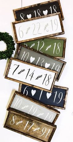 four wooden signs with numbers and hearts hanging on the wall in front of a wreath