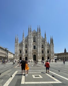 people are walking around in front of a cathedral