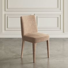 a beige chair sitting in front of a white wall