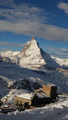 a snow covered mountain with a building in the foreground