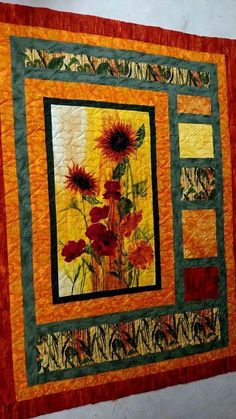 a quilted wall hanging with sunflowers on it