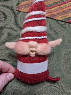 a hand holding a red and white gnome hat