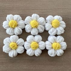 four white and yellow flowers on a wooden surface