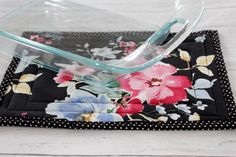 a glass casserole dish sitting on top of a black placemat with flowers