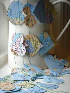 some paper hearts hanging from a string on a window sill in front of a cup