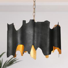 a black and gold chandelier hanging from a ceiling in a room with a potted plant