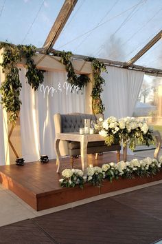 a stage set up with white flowers and greenery