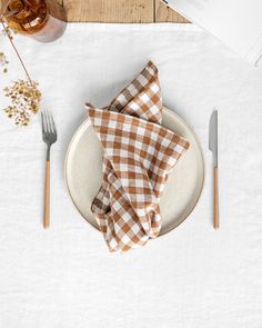 a white plate topped with a brown checkered napkin