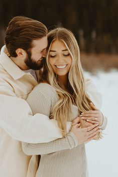 a man and woman hugging each other in the snow