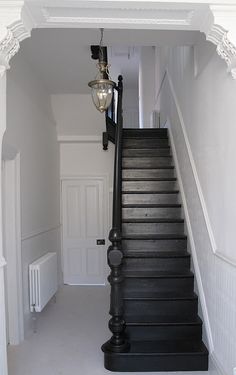 a staircase leading up to a white door and light hanging from the ceiling above it