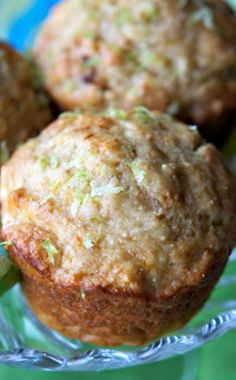 three muffins sitting on top of a glass plate next to a green leaf