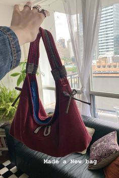 a person is holding a red purse in front of a window with cityscape