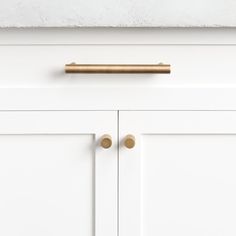 a white cabinet with brass handles and knobs