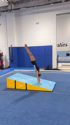 a person doing a handstand on a trampoline in an indoor gym