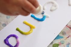 a child's hand is writing letters on paper