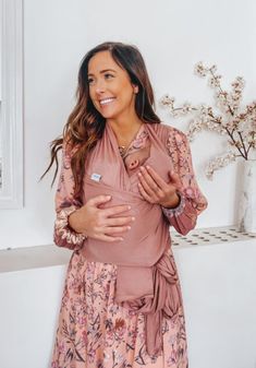 a woman standing in front of a white wall wearing a pink shirt and floral skirt