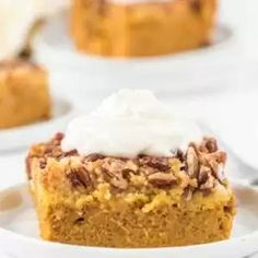 a close up of a piece of cake on a plate with whipped cream and pecans