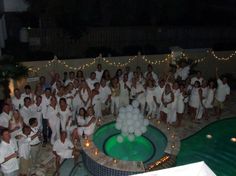 a group of people posing for a photo in front of a fountain with lights on it