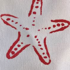 a red and white cross stitched starfish with dots on it's side