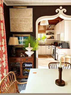 a dining room table and chairs in front of a kitchen with an archway leading into the living room