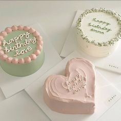 three birthday cakes with frosting in the shape of hearts