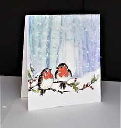 two birds are sitting on a branch in the snow, one is red and the other is white