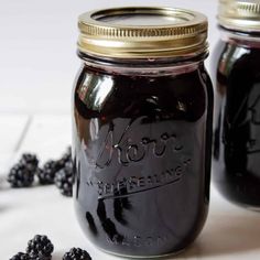 two jars filled with blackberries sitting on top of a table