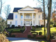 a large white house surrounded by trees and bushes