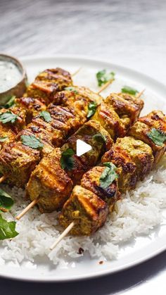 chicken kabobs on skewers with white rice and garnishes