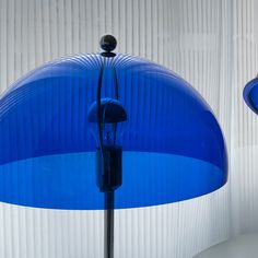 two blue lamps are next to each other in front of a white curtained wall