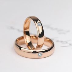 two gold wedding rings sitting on top of each other