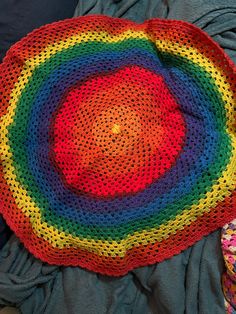 there is a crocheted rainbow rug on the bed