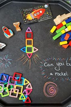 a chalkboard with magnets and toys on it that says can you build a rocket?