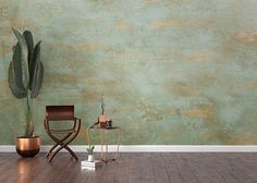 an empty room with a chair, table and potted plant in front of the wall